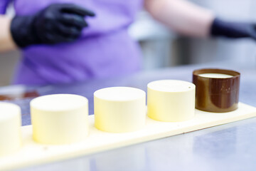 pastry maker fills round chocolate glasses with the filling. manufacture of confectionery products from milk chocolate and cream.
