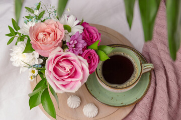 Delicate bouquet of summer flowers and a cup of black coffee in bed, summer morning concept