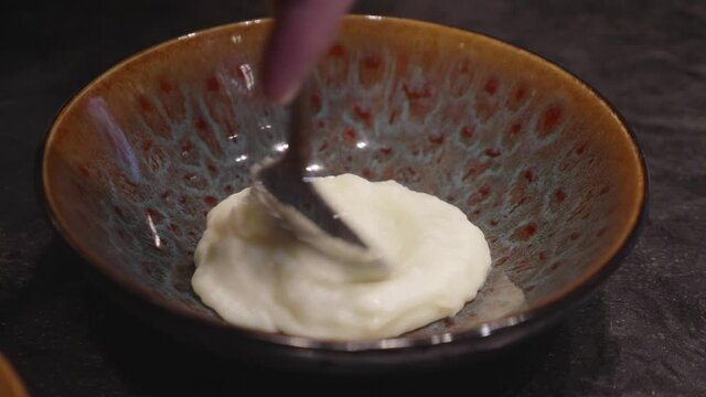 Chefs makes plating of meat and mashed potato dish, adding bits of green veggies nn top. Close up, slow motion shot.