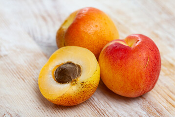 Naklejka na ściany i meble Sweet ripe whole apricots and juicy halves on wooden surface. Healthy vitamin product.