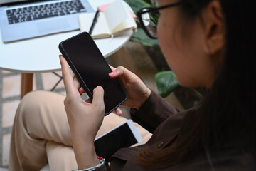 Over shoulder view of businesswoman sitting at cafe and using mobile phone.