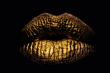 Golden lips closeup on balck. Gold metal lip. Beautiful makeup. Golden lip gloss on beauty female...