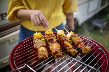 Friends making barbecue BBQ grilling over a hot fire  in the nature.Dinner party