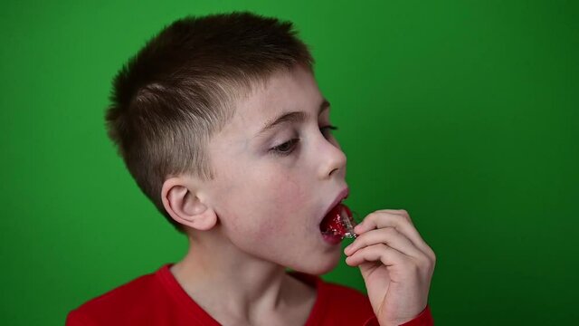 The child puts a plate on the teeth, slow motion, side view of a child, a boy on a green background.