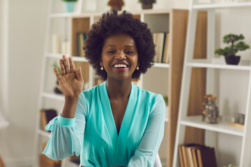 Friendly african american business woman waving her hand in greeting over a video call. Female...