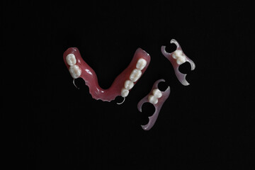 Dentures on a black background. Close-up of dentures. Dentistry is conceptual photography. Prosthetic dentistry. False teeth. Prosthetics. Close-up of plastic dentures. Teeth on a black background