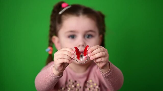The child examines and demonstrates a dental plate to straighten crooked teeth.