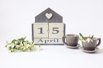 Calendar for April 15 :cubes with the number 15, the name of the month in English, two gray coffee...