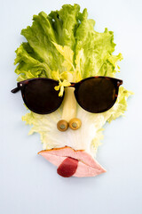 creative concept, cubist style portrait made from lettuce, apio, pastrami and olives, with sun glasses, isolated on white