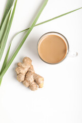 Glass cup of hot ginger tea with ginger rhizome (root) sliced isolated on white background.
