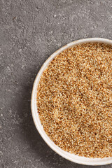 Sesame seeds in a bowl on a gray concrete background.