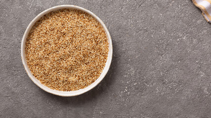 Sesame seeds in a bowl on a gray concrete background.