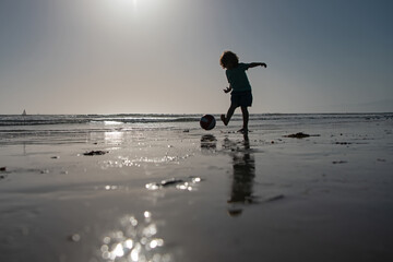 Fototapeta na wymiar Kod play soccer or football on the beach on summer holidays, silhouette on sunset.