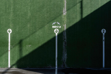 fronton wall in the Basque ball sport, in which the game marks are painted with the numbers 3 in the middle and 2 and 4 on both sides. Above the number 3 there are two Basque flags and the word, Motz,