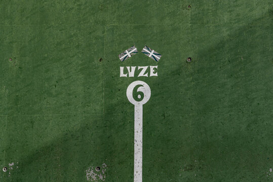 fronton wall in the Basque ball sport, in which the game marks with the number
 6 Two Basque flags appear above number 6 and the word, Luze, strong, in Basque, not strong enough, painted in negative i