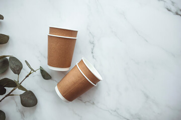 Set of disposable coffee nug and table ware, eco friendly. Disposable cardboard cup with empty space for text on gray background. Take out coffee or delivery service. Copy space.