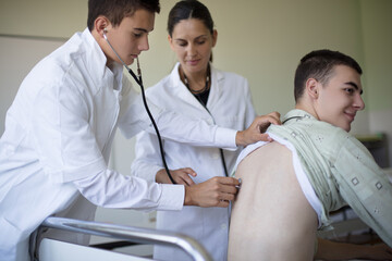 Young student checks a patient's lungs in a hospital room.