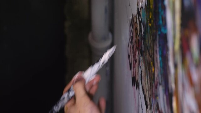Artist designer draws an eagle on the wall. Craftsman decorator paints a picture with acrylic oil color. Close-up dark magic cinematic look.
