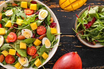 Plate of fresh mango salad on dark wooden background