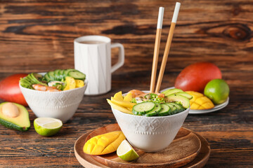 Bowl of fresh salad with mango, shrimps and vegetables on wooden background