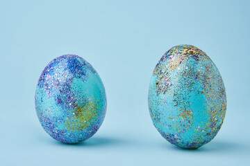 Blue painted eggs with bright shiny gliter on blue background