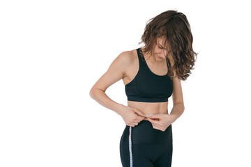 The girl measures her waist. Isolate with a girl in a sports black suit