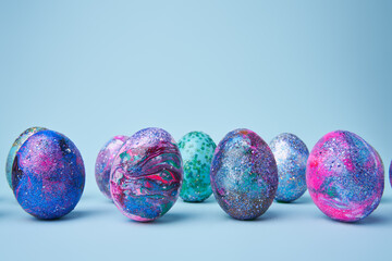 Colorful painted shiny eggs on blue background.