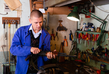 Gunsmith checks Kalashnikov assault rifle in a weapons workshop