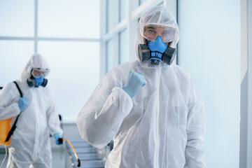 image of a confident disinfector standing in an office lobby .