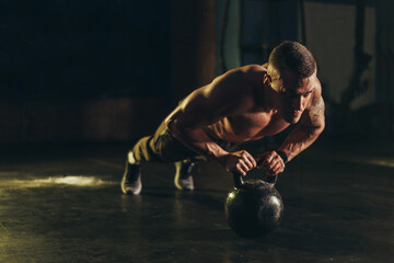 Man doing pushups with kettlebell in the gym
