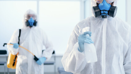 young disinfector with a bottle of antiseptic standing in the ro