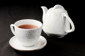 Tea cup with tea pot over black background. Tea time.