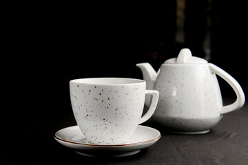 Tea cup with tea pot over black background. Tea time.