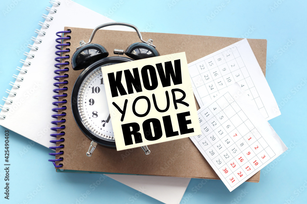 Poster know your role. text on the sticker attached to the alarm clock. alarm clock on notepad on blue back