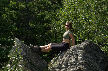 Naklejka na ściany i meble Relaxed touristic woman sit on a stone in mountain forest
