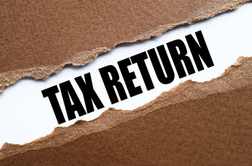 Tax Return. text on white paper over torn paper background.