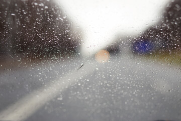 Abstract blurred background of drops and drips of rain water on the windshield glass of the car