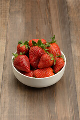 Fresas en un bol en la mesa, fondo marrón