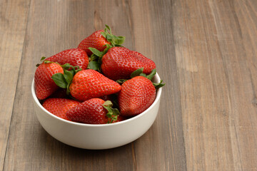 Fresas en un bol en la mesa, fondo marrón