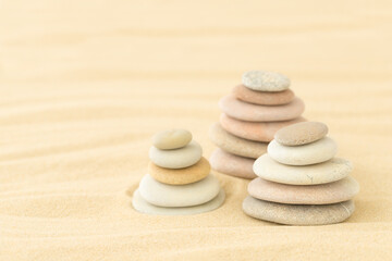 Fototapeta na wymiar Sea pebbles stacked on top of each other in the sand - a summer backdrop for relaxation