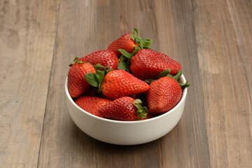 Fresas en un bol en la mesa, fondo marrón