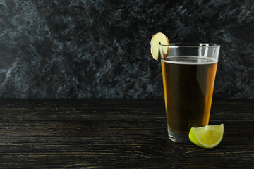 Glass of ginger beer and ingredient on wooden table