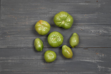Unripe green tomatoes on a dark wooden table. Horizontal orientation