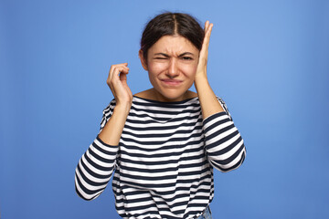 Portrait of unhappy stressed young European woman posing isolated in striped shirt having water in...