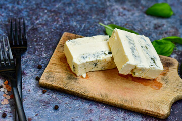 Gorgonzola cheese on cutting board with fresh  basil . Veined Italian  blue cheese.