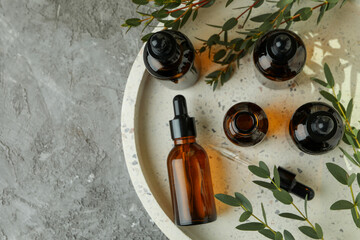 Tray with bottles of eucalyptus oil and branches on gray table