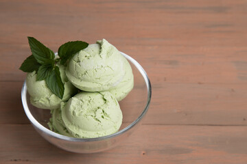 Glass cup with matcha green tea ice cream balls on wooden background . The concept of delicious healthy desserts