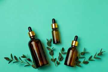 Brown bottles of eucalyptus oil and twigs on mint background