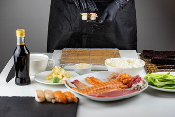 Close up of sushi chef hands preparing japanese food. Man cooking sushi at restaurant. Traditional asian seafood rolls on cutting board.