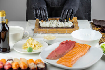 Close up of sushi chef hands preparing japanese food. Man cooking sushi at restaurant. Traditional asian seafood rolls on cutting board.